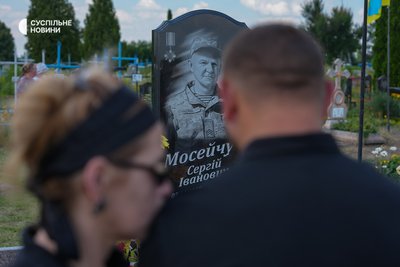 Serhiy Moseychuk, the youngest son in the family, with his wife near the grave of their father Serhiy Moseychuk, who died in 2023 near Kupyansk. His two older brothers, who were abducted and killed, are buried next to their father. Kalynivka, July 15, 2026