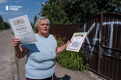 Lyudmyla Ryabkina, the own sister of ex-brigade commander Luchanov's mother-in-law, shows her thanks from the military for baking them cookies in front of her house. Kalynivka, July 13, 2026
